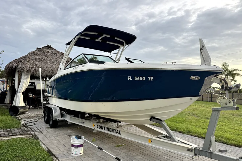 Slide: The Image of 2022 Cobalt R6 Outboard boat on trailer, parked near a thatched-roof structure. - 3