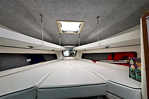 Slide: The Image of 2003 Contender 35 Side Console cabin interior with white upholstery and overhead hatch. - 14