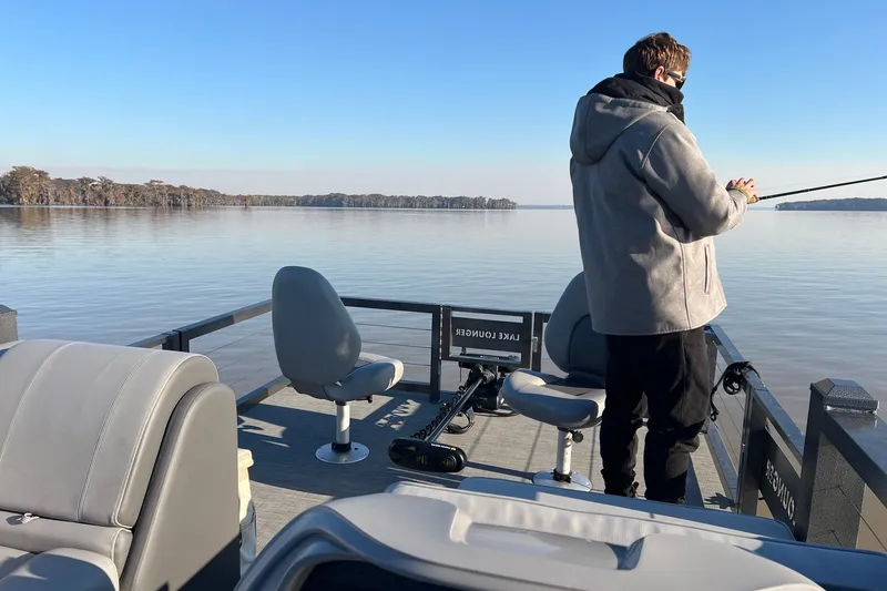 Slide: The Image of Man fishing on a 2026 Lake Lounger 16' Front Fish Pro boat on a serene lake. - 15