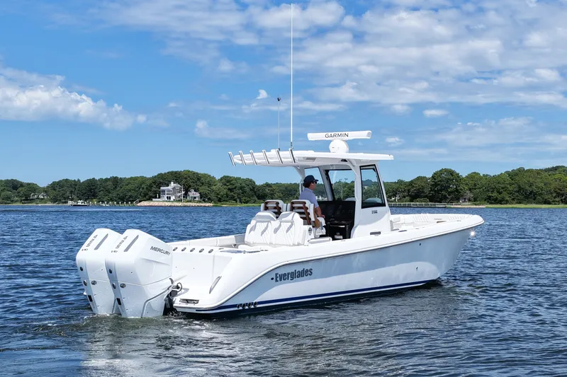 Slide: The Image of 2027 Everglades 315 Center Console boat cruising on a scenic lake under a blue sky. - 6