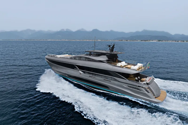 Slide: The Image of 2024 Mangusta GranSport 33 yacht cruising on open sea with mountainous coastline backdrop. - 2