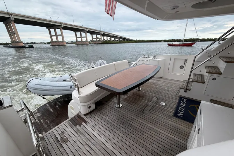 Slide: The Image of Luxury Horizon E56 yacht deck with seating, table, and scenic bridge view. - 21