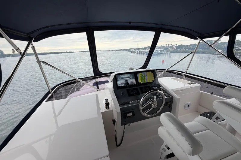 Slide: The Image of Helm of 2020 Horizon E56 yacht with navigation screens, steering wheel, and waterfront view. - 49