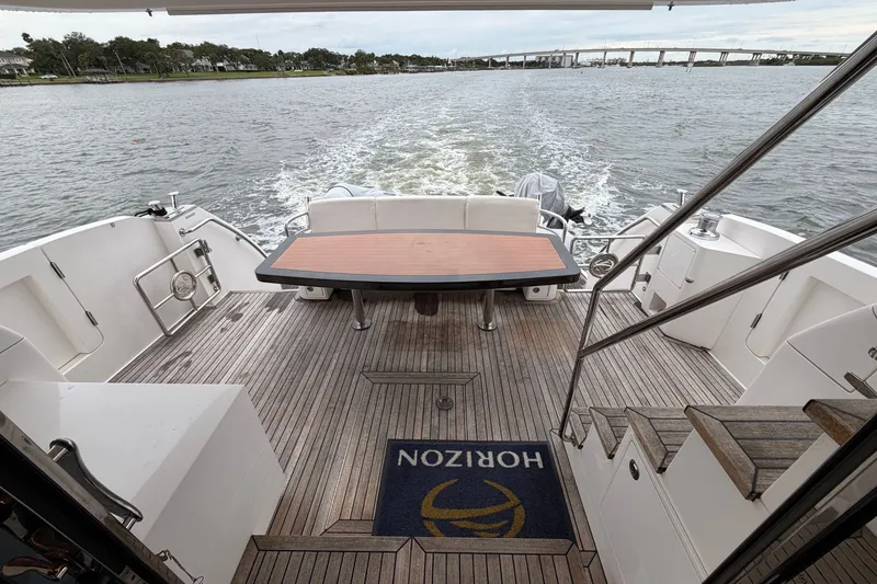 Slide: The Image of Luxury Horizon E56 yacht deck with wooden flooring, table, and scenic water view, 2020 model. - 45