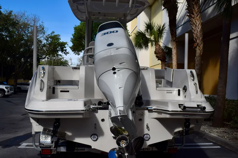 Slide: The Image of 2026 Sailfish 232 CC boat with powerful outboard motor, parked near palm trees. - 2