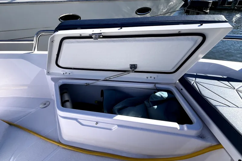 Slide: The Image of Open storage compartment on 2026 Axopar 29 XC Cross Cabin boat, docked by water. - 35