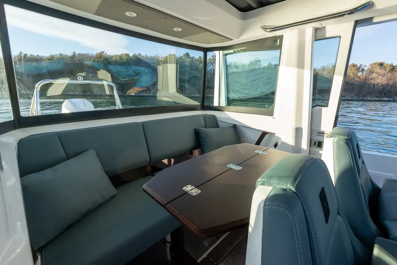 Slide: The Image of Interior of 2026 Axopar 29 XC Cross Cabin with seating and table, scenic water view. - 29