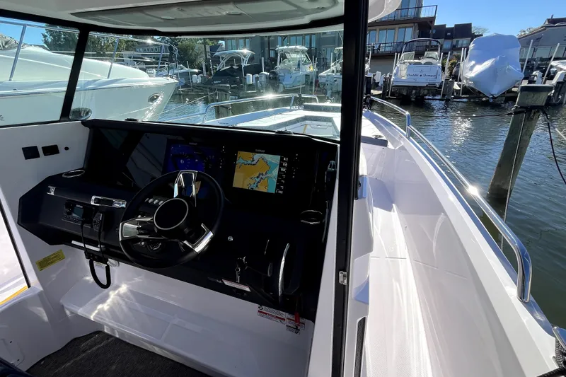 Slide: The Image of 2026 Axopar 29 XC Cross Cabin helm with navigation display, docked in marina. - 30