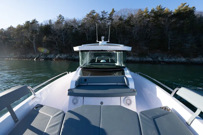 Slide: The Image of 2026 Axopar 29 XC Cross Cabin boat on calm water near forested shoreline. - 13