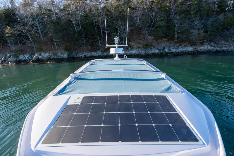 Slide: The Image of 2026 Axopar 29 XC Cross Cabin with solar panels on a serene waterway. - 24