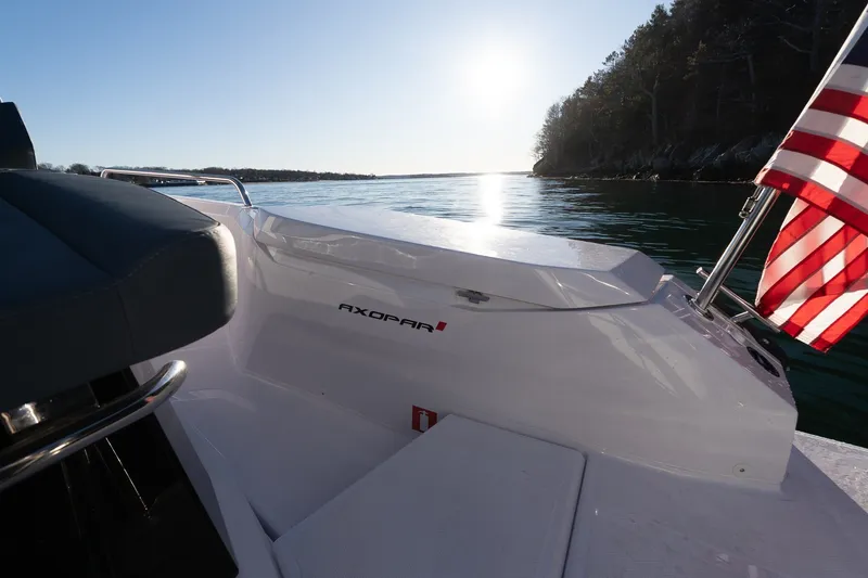 Slide: The Image of 2026 Axopar 29 XC Cross Cabin boat on calm water with American flag. - 22