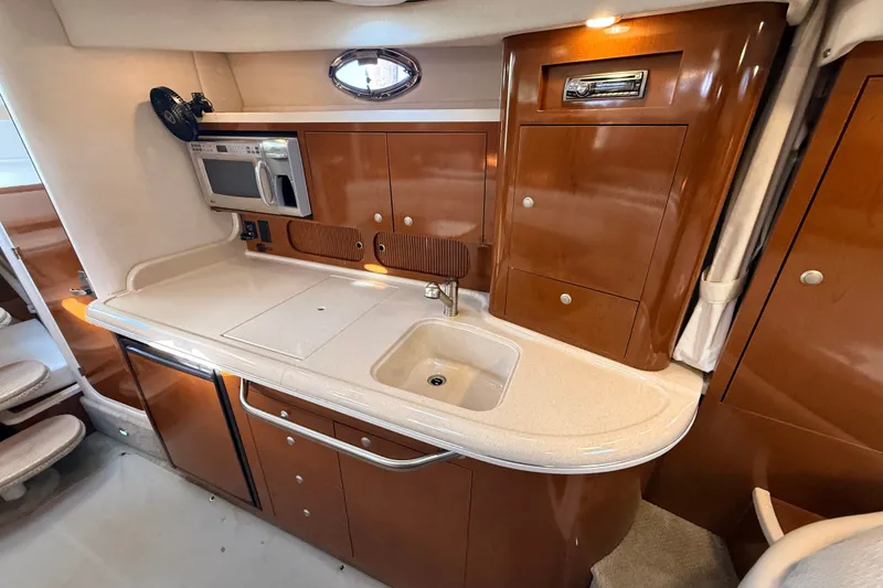 Slide: The Image of 2008 Sea Ray 340 Sundancer galley with sink, microwave, and wooden cabinetry. - 32