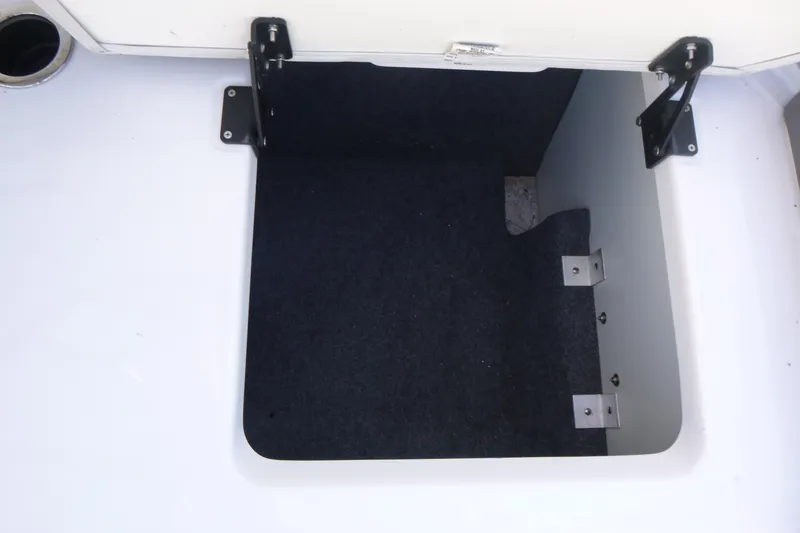 Slide: The Image of Open storage compartment in 2022 Yamaha AR250 boat, featuring carpeted interior and sturdy hinges. - 15