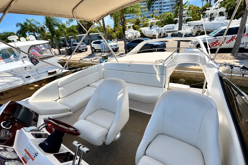 Slide: The Image of 2009 Regal 4080 Sportyacht interior with white seating and helm, docked near palm trees. - 3