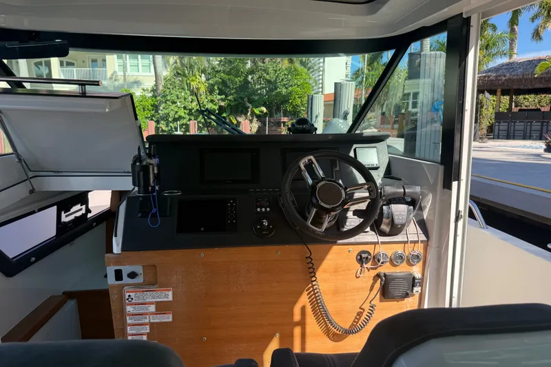 Slide: The Image of 2018 Axopar 37 Sports Cabin helm with steering wheel and control panel. - 11