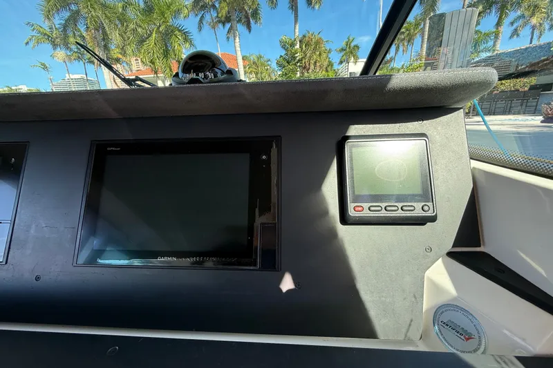 Slide: The Image of Dashboard of 2018 Axopar 37 Sports Cabin with Garmin GPS, palm trees visible outside. - 15