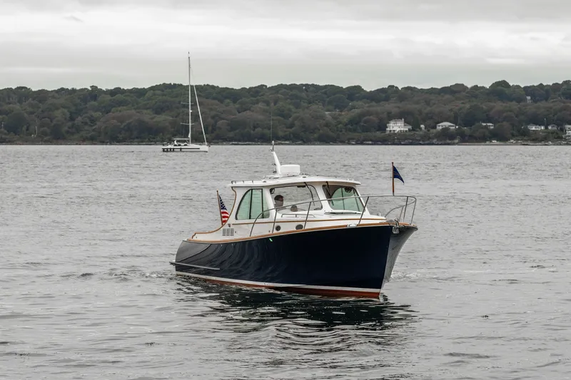 Slide: The Image of 2013 Hinckley Talaria 34 cruising on a calm lake with forested shoreline. - 2