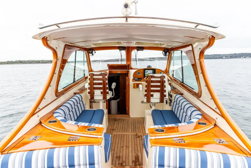 Slide: The Image of 2013 Hinckley Talaria 34 boat interior with striped seating and wooden accents on open water. - 16