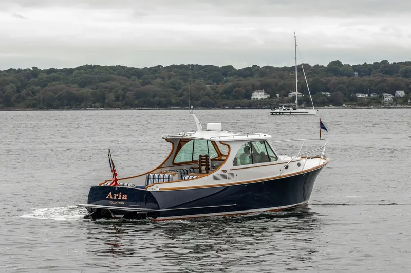 Slide: The Image of 2013 Hinckley Talaria 34 yacht cruising on a calm lake with wooded shoreline. - 3