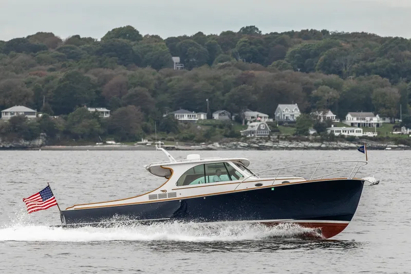 Slide: The Image of 2013 Hinckley Talaria 34 cruising on water with coastal homes in the background. - 6