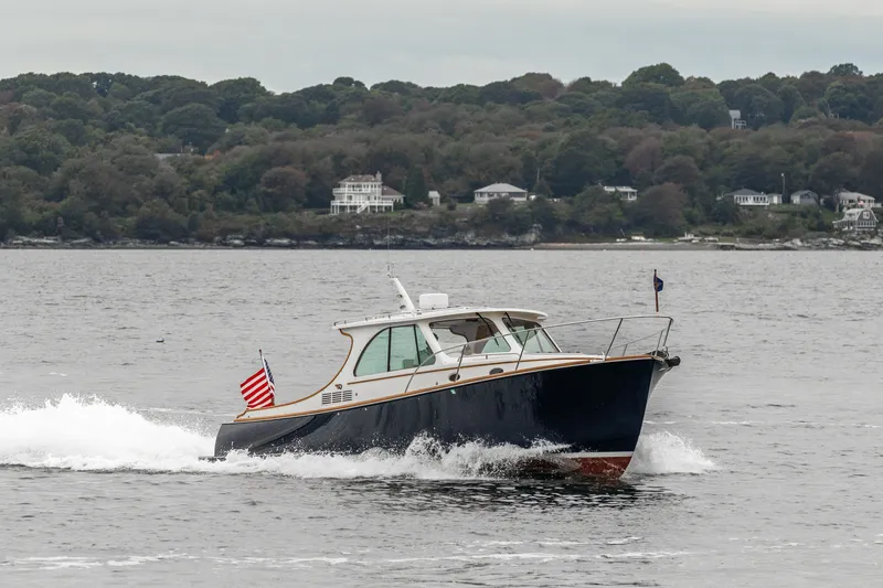 Slide: The Image of 2013 Hinckley Talaria 34 cruising on water with scenic shoreline backdrop. - 11
