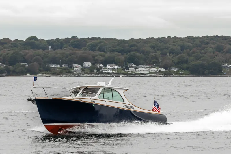 Slide: The Image of 2013 Hinckley Talaria 34 cruising on water with scenic shoreline background. - 5