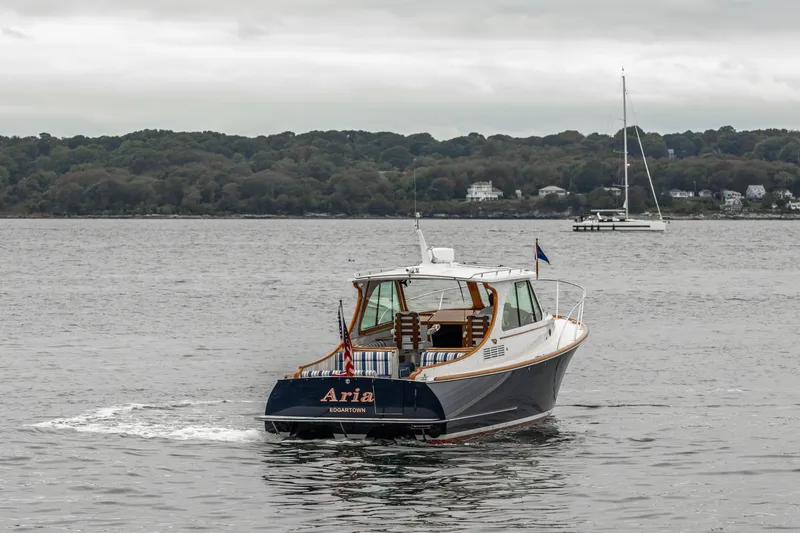 Slide: The Image of 2013 Hinckley Talaria 34 cruising on a calm lake with a sailboat in the background. - 0