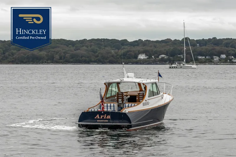 Slide: The Image of A 2013 Hinckley Talaria 34 cruising on calm waters with a wooded shoreline in the background. - 0
