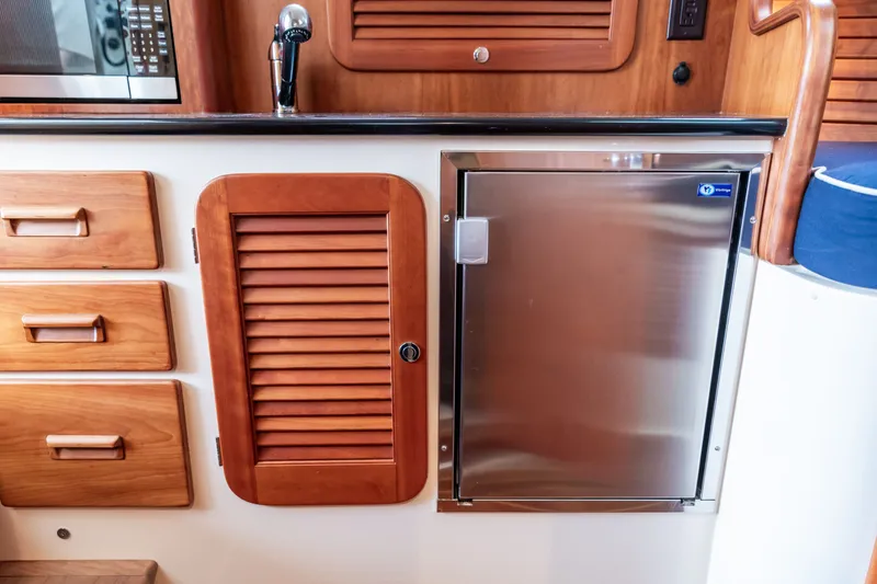 Slide: The Image of Hinckley Talaria 34 (2013) interior with wooden cabinetry and stainless steel fridge. - 28