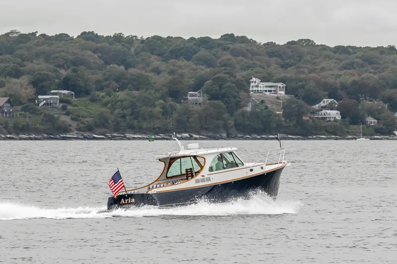 Slide: The Image of 2013 Hinckley Talaria 34 cruising on water with scenic shoreline background. - 7