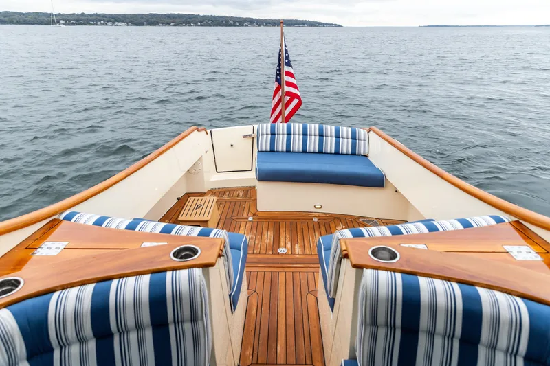 Slide: The Image of Hinckley Talaria 34 yacht deck with striped seating, American flag, and ocean view. - 12