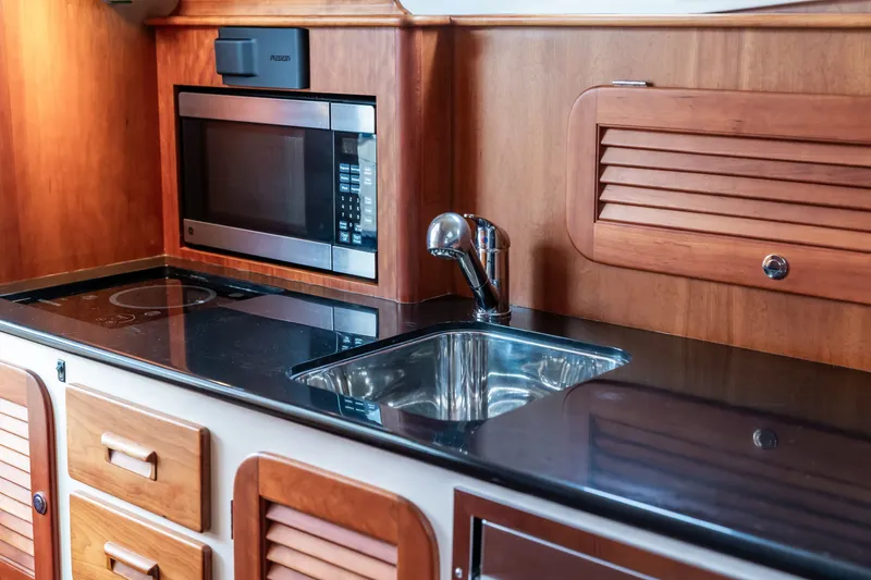 Slide: The Image of Hinckley Talaria 34 yacht kitchen with microwave, sink, and wooden cabinetry, 2013 model. - 27