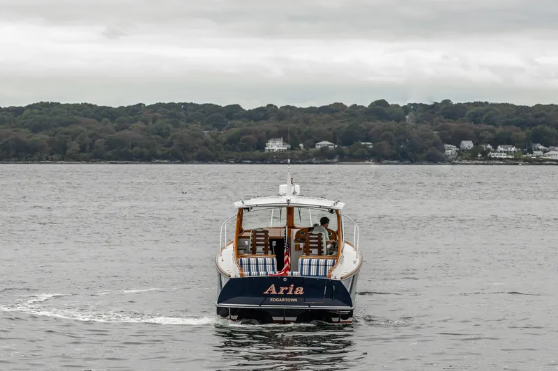 Slide: The Image of 2013 Hinckley Talaria 34 boat cruising on a calm lake with forested shoreline. - 4