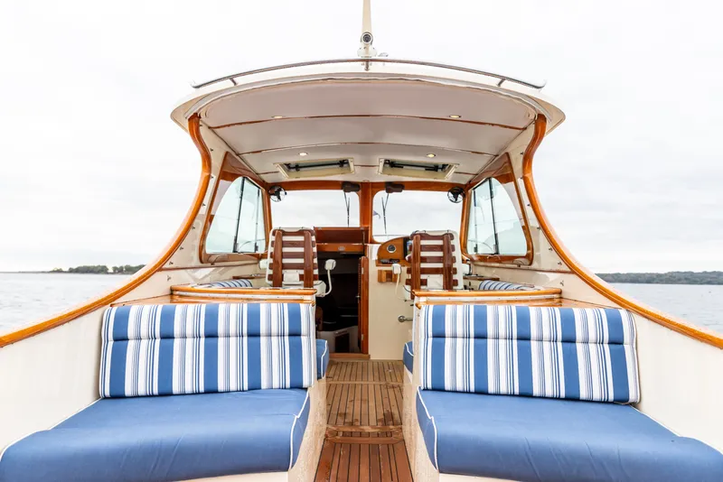Slide: The Image of 2013 Hinckley Talaria 34 boat interior with striped seating and wooden accents on open water. - 15