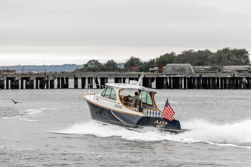 Slide: The Image of 2013 Hinckley Talaria 34 boat cruising near a pier, displaying an American flag. - 9