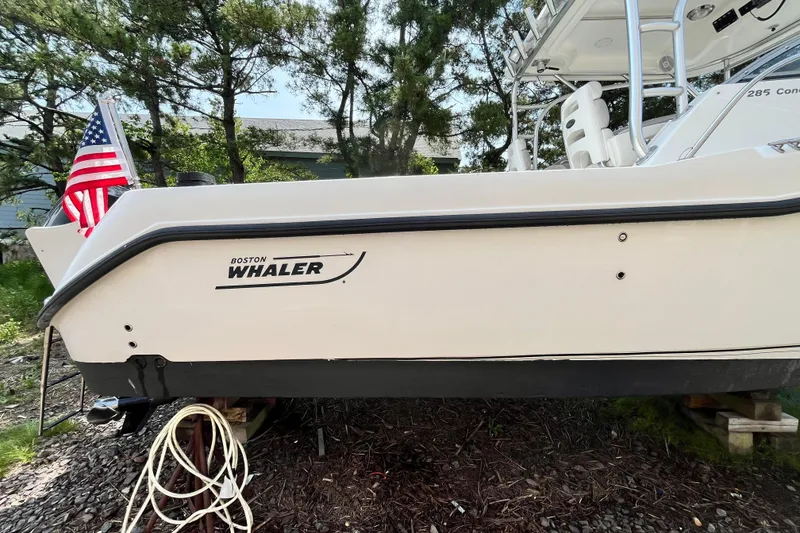 Slide: The Image of 2006 Boston Whaler 285 Conquest boat with American flag, docked on land. - 8