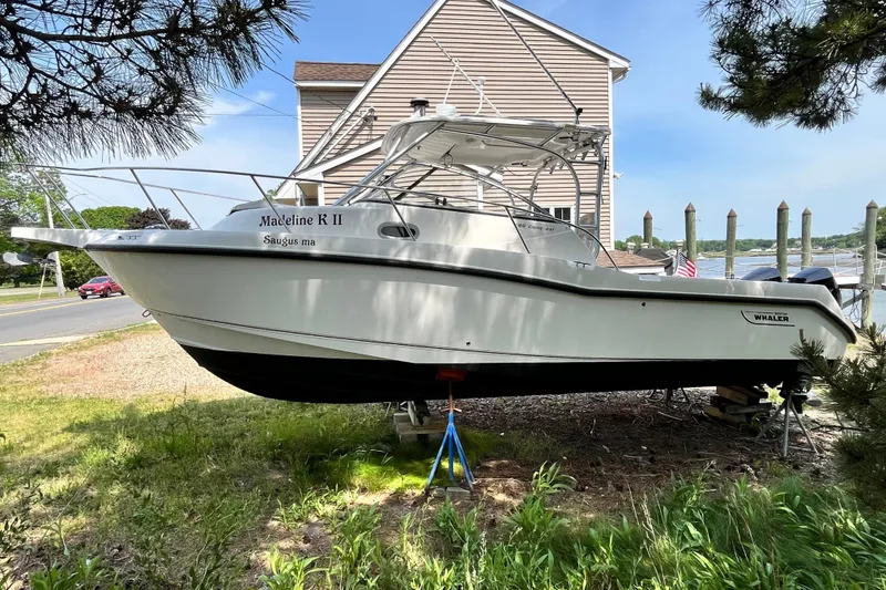 Slide: The Image of 2006 Boston Whaler 285 Conquest boat on land, near a waterfront setting. - 1