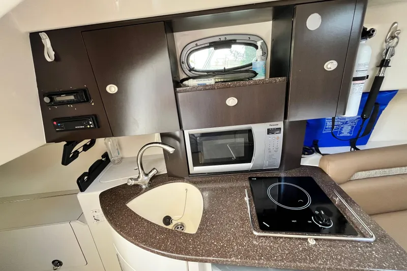 Slide: The Image of 2006 Boston Whaler 285 Conquest cabin kitchen with sink, microwave, and stovetop. - 35