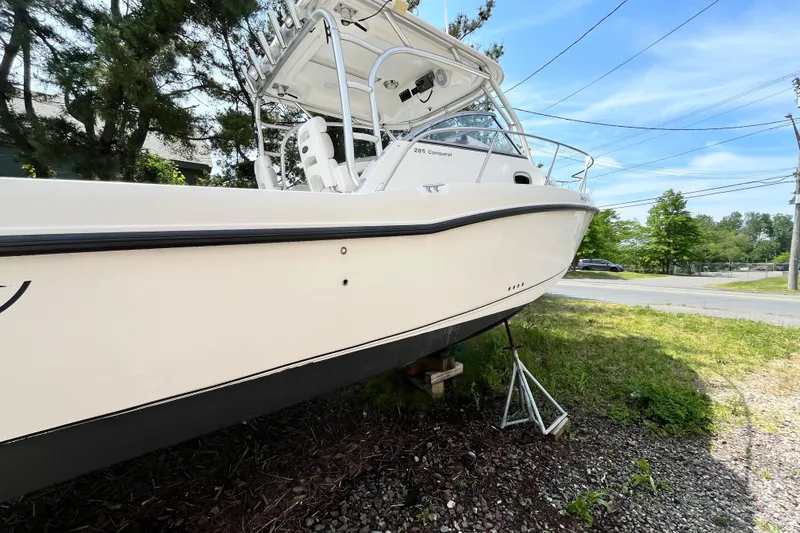 Slide: The Image of Boston Whaler 285 Conquest 2006 boat on land, surrounded by trees and a clear sky. - 9