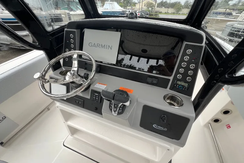 Slide: The Image of 2027 Robalo R250 Center Console boat dashboard with Garmin navigation system and steering wheel. - 16