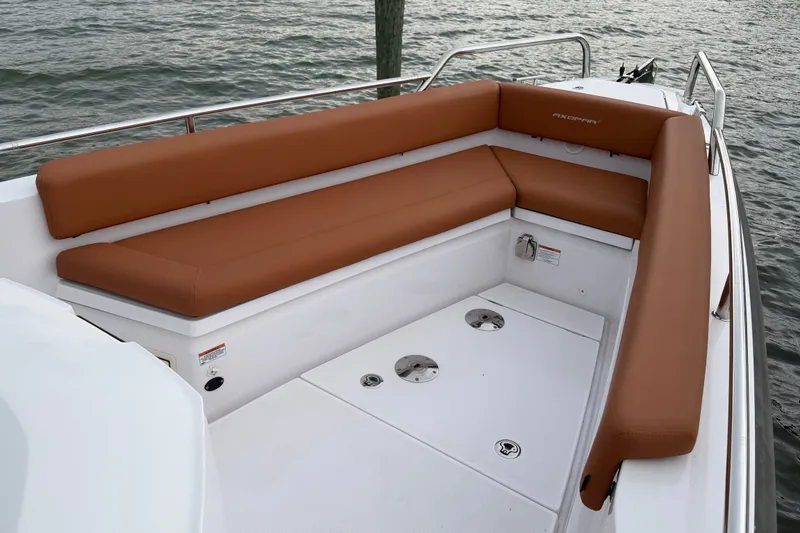 Slide: The Image of 2023 Axopar 28 Cabin boat with brown cushioned seating, docked by the water. - 31