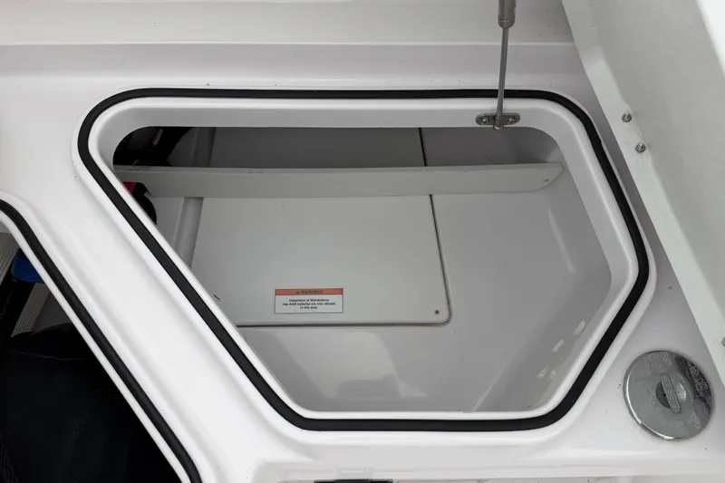 Slide: The Image of Storage compartment of 2023 Axopar 28 Cabin boat, featuring a secure latch and warning label. - 33