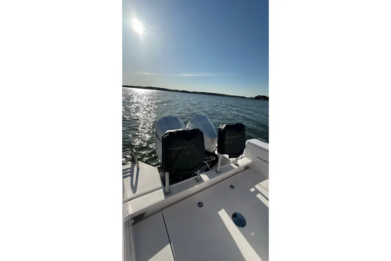 Slide: The Image of 2023 Axopar 28 Cabin boat on water, featuring dual engines under a sunny sky. - 47