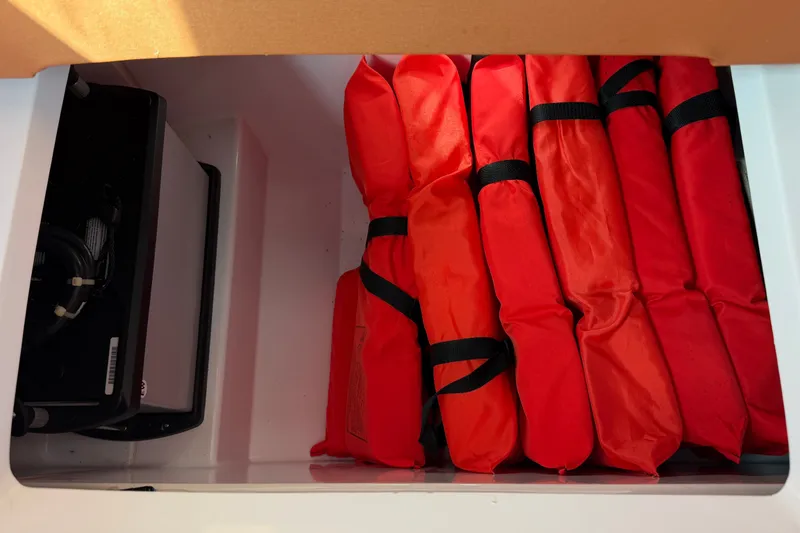 Slide: The Image of Storage compartment with red life jackets in a 2023 Axopar 28 Cabin boat. - 23