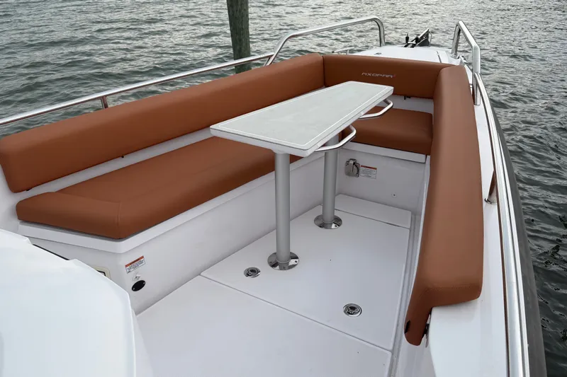 Slide: The Image of 2023 Axopar 28 Cabin boat with brown seating and a white table on deck. - 30