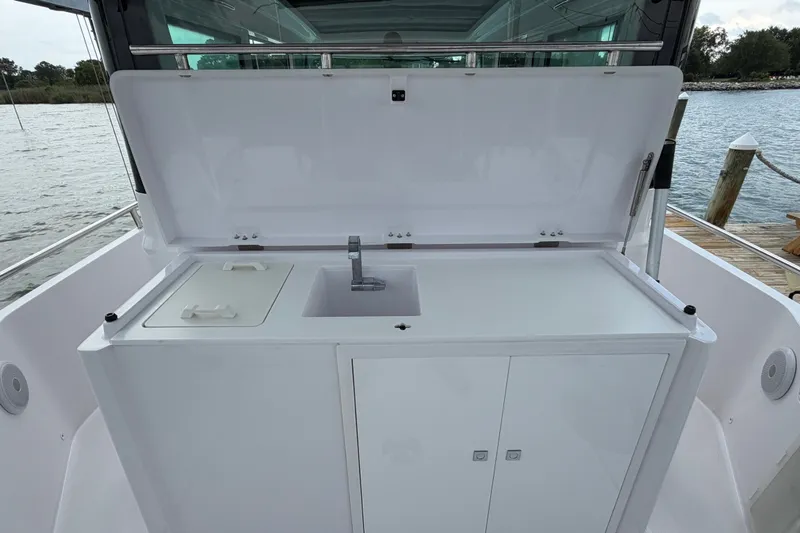 Slide: The Image of 2023 Axopar 28 Cabin boat with open storage compartment and sink on deck. - 41