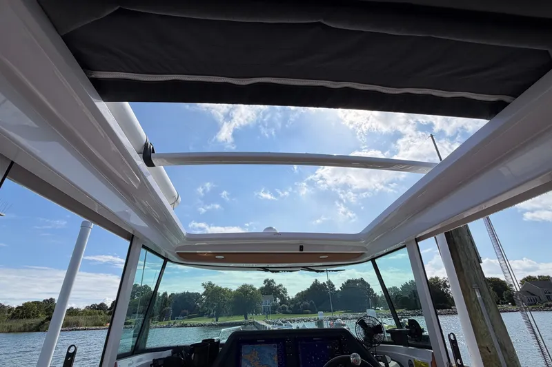 Slide: The Image of 2023 Axopar 28 Cabin interior view with open roof, showcasing clear sky and water. - 26