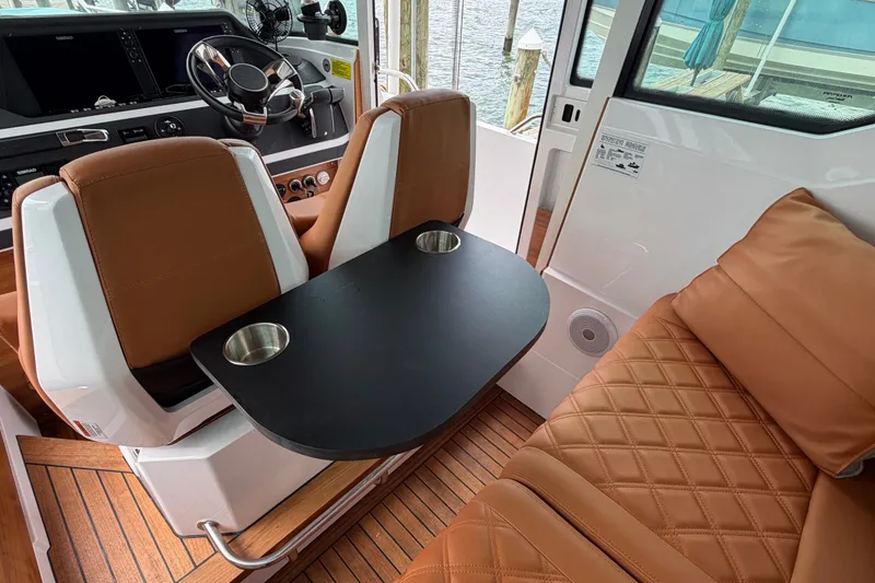 Slide: The Image of Interior of 2023 Axopar 28 Cabin with brown leather seating and black table. - 18