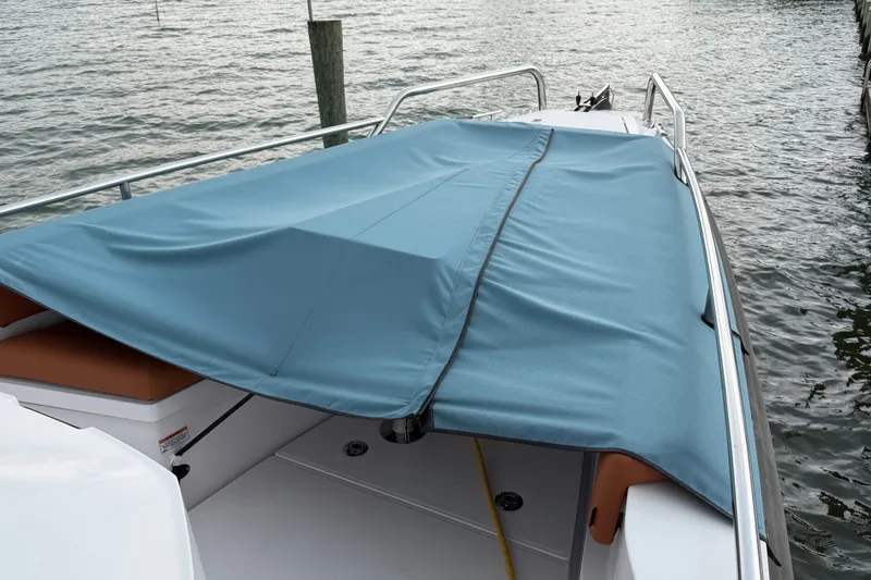 Slide: The Image of 2023 Axopar 28 Cabin boat with blue cover docked on water. - 29