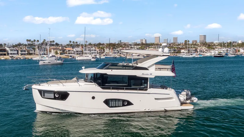 The Image of Die Absolute Navetta 48 von 2020 fährt auf ruhigem Wasser mit einer Stadt im Hintergrund. - 0